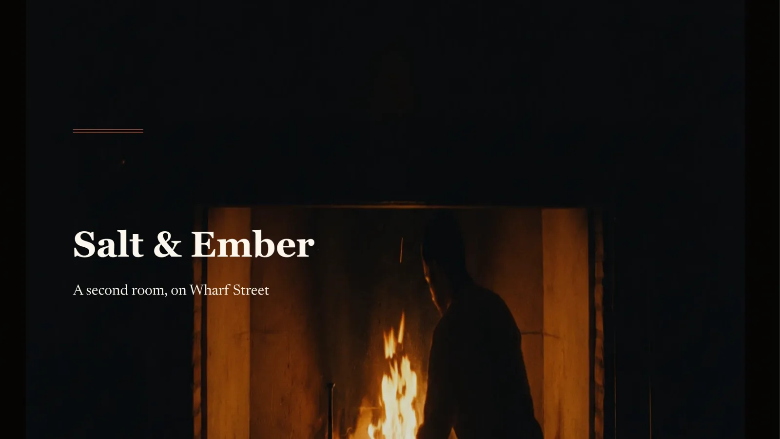 Title slide for Salt and Ember, a restaurant. A near-black cinematic frame with a single wood fire burning in an open kitchen hearth and a chef silhouetted against it; the name set in a high-contrast serif at the lower left.